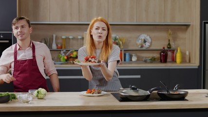 Cooking show hosts chefs, male and female, showing cooked dish into camera. Morning TV cooking...