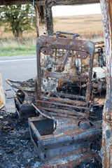The burned out wreckage of an old van in a road layby 