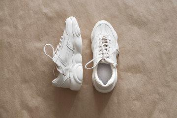 A pair of light-colored sneakers on craft wrapping paper. Minimalistic shoe background, fashion...