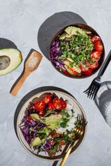 Flatlay of two vegan tofu poke bowls on a grey background, selective focus