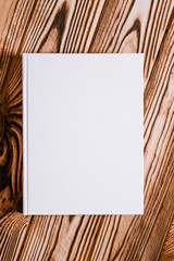 Mockup of the white book with a place for text lies on a textured wooden background