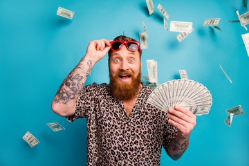 Photo of excited macho guy hold fan usa bucks good mood money luxury rich person dollars fall income lottery cashback wear leopard shirt sun specs isolated blue background - obrazy, fototapety, plakaty