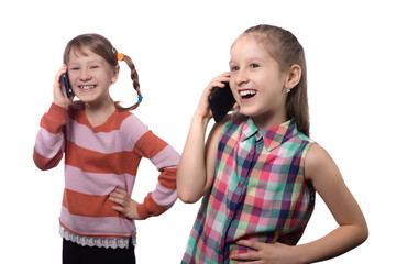 Two cute little girls posing with mobile phones.