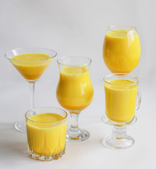 Golden milk with turmeric in different glasses on white background. Healthy spicy curcuma drink concept. Trendy minimal food