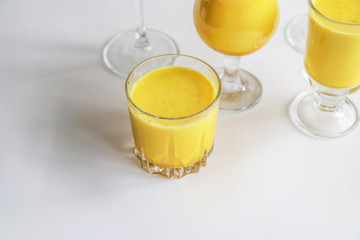 Golden milk with turmeric in different glasses on white background. Healthy spicy curcuma drink concept. Trendy minimal food