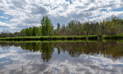 landscape with a beautiful river in spring, cloud reflections in the water