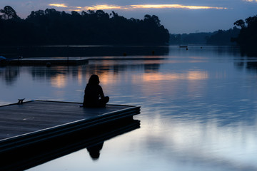 Alone women relax on wooden dock at peaceful lake