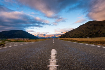 A long straight road with raining cloud and Mountain in evening