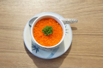 orange Caplin roe  Japanese food on top with green vegetable in white cup white plate with spoon on wood background