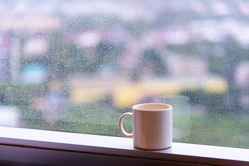 break time with a cup of coffee during raining at window with city view