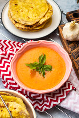 Orange pumpkin carrot creamy vegetables soup in bowl with rucola herb on top. Vegan food lunch