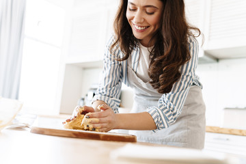 Image of caucasian smiling woman kneading dough for sweet pie