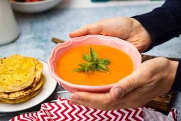 Orange pumpkin carrot creamy vegetables soup in bowl with rucola herb on top. Vegan food lunch