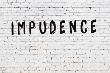 Word impudence painted on white brick wall