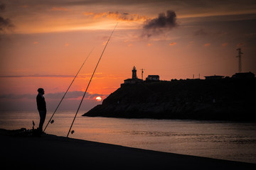 Pescador al atardecer un dia de verano pesca junto a la orilla