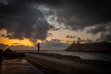 Pescador al atardecer un dia de verano pesca junto a la orilla