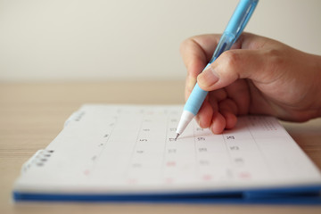 Hand with pen writing on calendar date