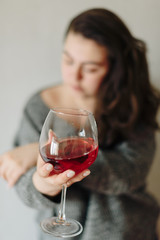 close-up of a girl in a grey sweater with a glass of red wine