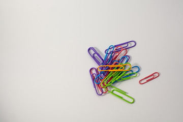 Colored paper clips lie together. Around white background. Blue, yellow, purple, green, pink and orange. Plastic paper clips for documents. Office and educational equipment. Tools for paper work. Orde