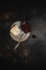 Blue cheese and grape, olives and dates on grey plate with knife on brown concrete background, copy space, wine snack