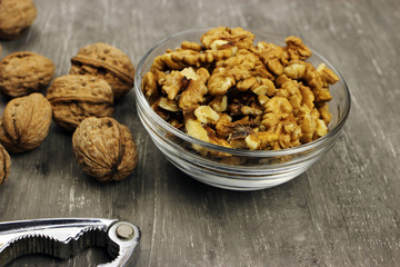 Walnut kernels in a bowl and whole nuts on an old gray table