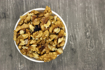 walnut kernels in a bowl on a gray background top view, copy space