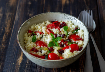 Couscous salad with tomatoes, peppers, courgettes and cranberries. Vegetarian food. Diet. Healthy eating.