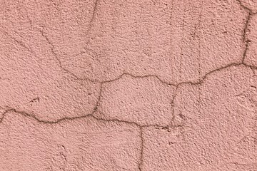 
Texture of pink cracked stucco with dark cracks.