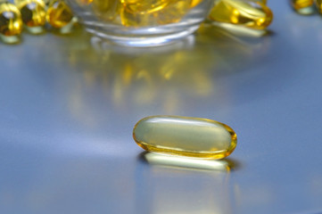 Fish oil capsules on a glass plate. A lot of vitamin omega 3. Close-up.