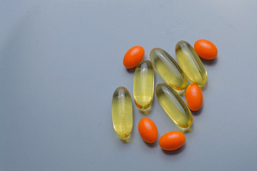 multi-colored pills and vitamins in capsules on a gray background. top view