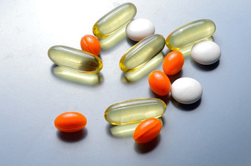 multi-colored pills and vitamins in capsules on a gray background. top view