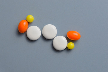 multi-colored pills and vitamins in capsules on a gray background. top view
