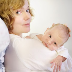 Mother holding her tiny newborn baby. Woman enjoy her first day's as a young mom with cute infant child. Mother day.