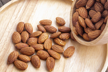 almonds in a wood bowl on grained wood background