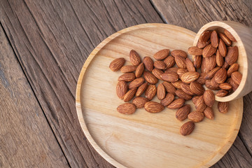 almonds in a wood bowl on grained wood background