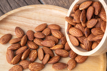 almonds in a wood bowl on grained wood background