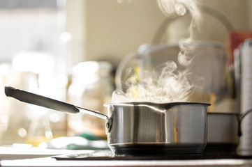 Boiling water with a steam in a pot on a electric stove in the kitchen
