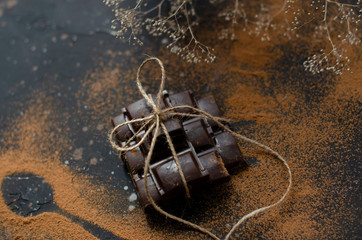 Fototapeta na wymiar pieces of dark chocolate tied with string and sprinkled with cocoa powder with dried oranges