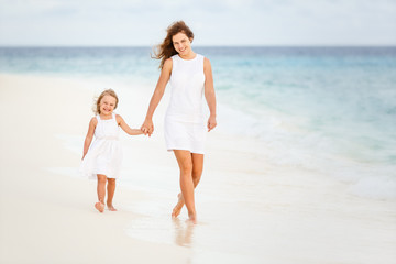 Mother and little daughter walking on beach on Maldives at summer vacation