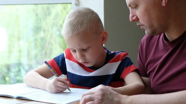 Father helping his little son to do school homework, indoors at home