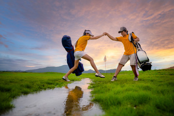 couple lover golf player in action of step jump over the water channel of the golf field raceway...