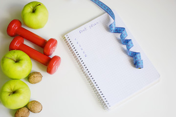 Planning diets, fruits and dumbbells on the background, top view