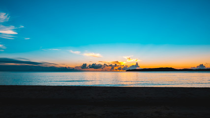 Obraz premium A beautiful sunset with a colorful bright blue sky at a tropical beach.