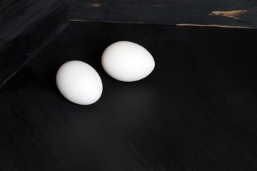 white chicken eggs on black wooden background