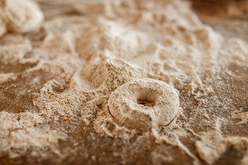 Dough in shape of a bagel on a table with flour.