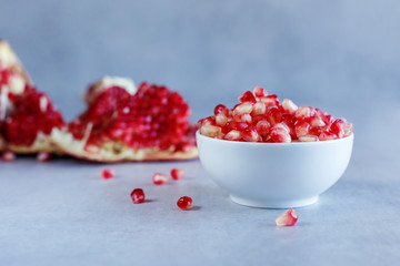 Ripe pomegranate seeds in white cup on a blue background. Healthy food.