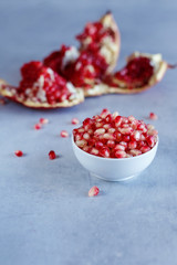 Ripe pomegranate seeds in white cup on a blue background. Healthy food.
