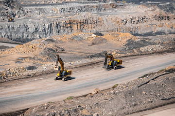 Concept open pit mine industry. Metaphor giraffes excavator moving end of working day