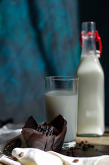 chocolate muffins on a table with a glass of milk and flowers