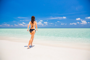 Fototapeta na wymiar Young woman in bikini enjoing the beautiful ocean beach on Maldives
